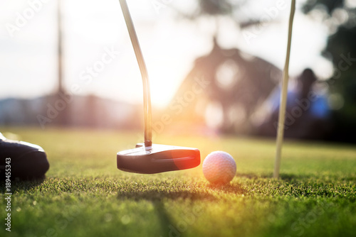 putter going to impact golf ball on the green to the hole by the player photo