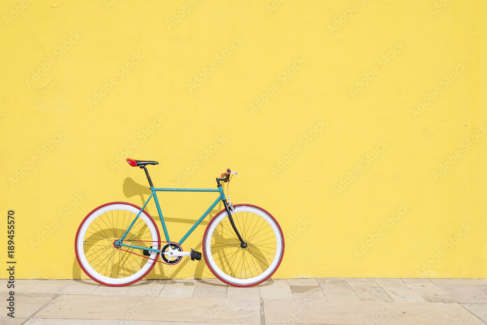 A City bicycle fixed gear on yellow wall