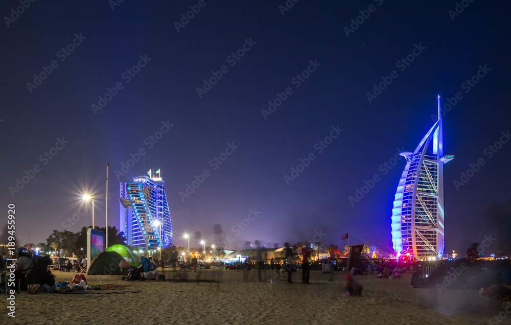 Fototapeta premium People waiting for new year celebration at the beach in last day of the year. The world's first seven stars luxury hotel Burj Al Arab and Dubai Marina in background 