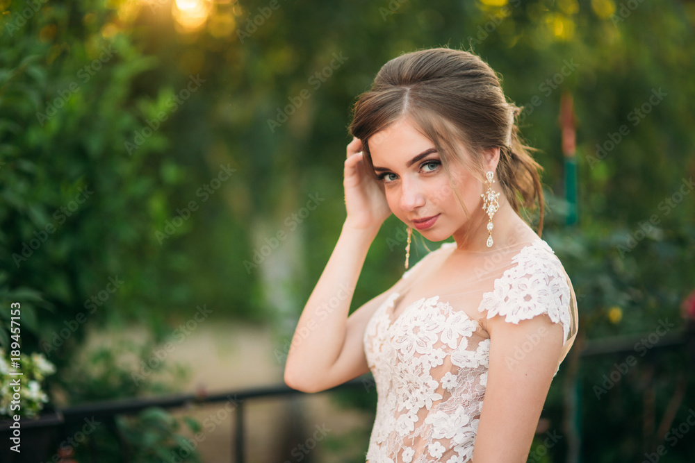 Young girl in wedding dress in park posing for photographer. Sunny weather, summer Young girl in wedding dress in park posing for photographer. Sunny weather, summer
