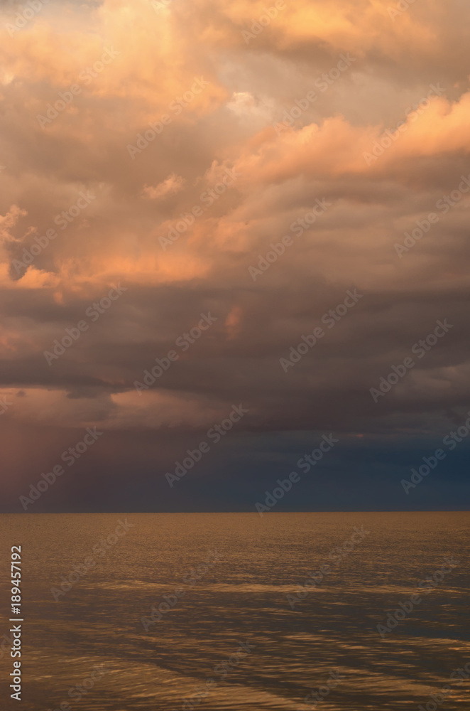 storm clouds on the Azov Sea, illuminated by the setting sun, the sea horizon. vertical composition.