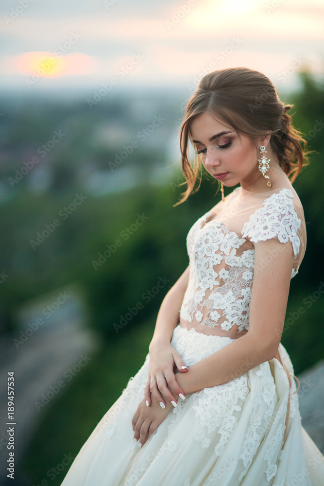 Young girl in wedding dress on city background at sunset. Summer Young girl in wedding dress on city background at sunset. Summer