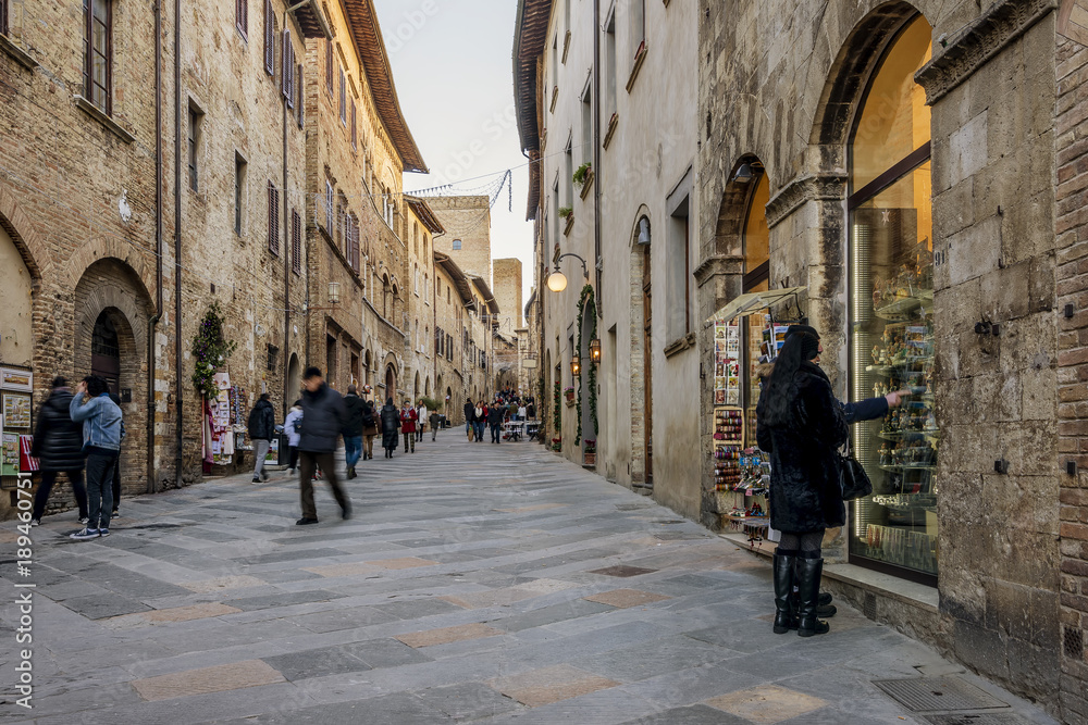People walking and shopping on the main street of the medieval village, San Gimignano, Siena, Tuscany, Italy