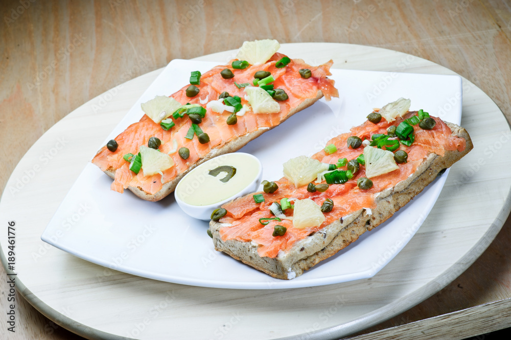 Salmon sandvich on white plate.