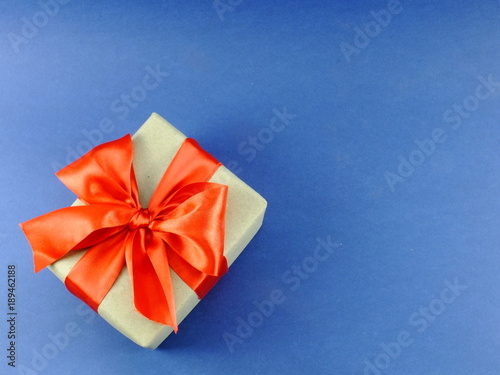 gift box wrapped in recycled paper with ribbon bow isolated on blue background