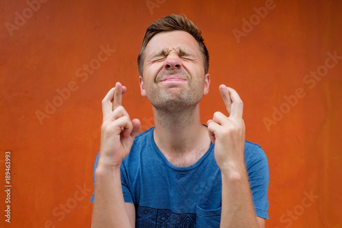 Young caucasian man making a wish isolated on red background photo