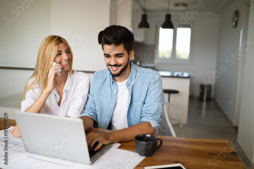 Handsome young man and attractive woman working on laptop