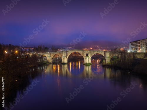 Puente Romano de Ourense iluminado al amanecer y reflejado en el rio Miño