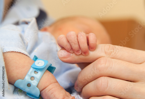The baby clings to his mother's finger photo