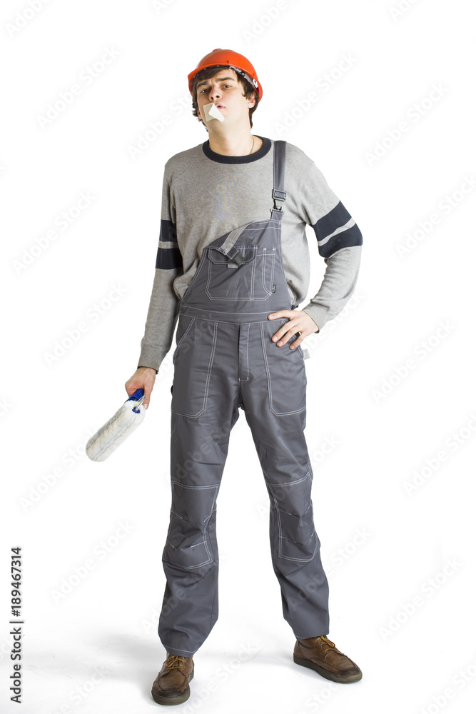 A young man in working grey clothes and orange hard helmet man with tape over mouth. Isolated on white background. A young man in working grey clothes and orange hard helmet man with tape over mouth. Isolated on white background.