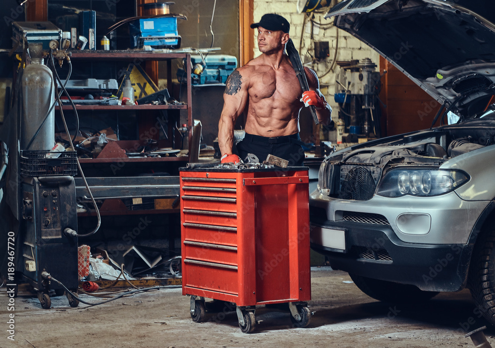 Shirtless mechanic in a garage. Stock Photo Adobe Stock