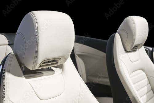 Modern Luxury car inside. Interior of prestige modern car. Comfortable leather seats. White perforated leather cockpit with isolated Black background. Modern car interior details