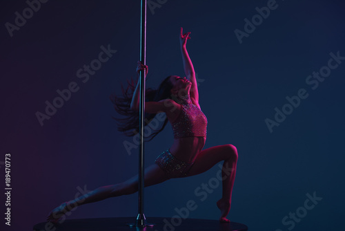 attractive sporty girl dancing with pole on blue