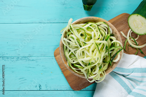 Raw zucchini noodles on a turquoise background