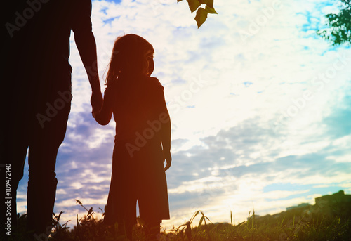 silhouette of father and daughter holding hands at sunset