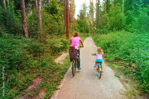 mother with kids riding bikes in summer nature