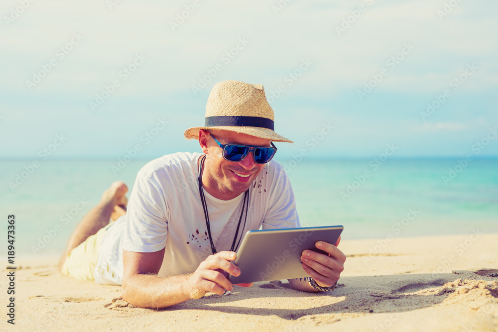 Young handsome man using tablet on the beach