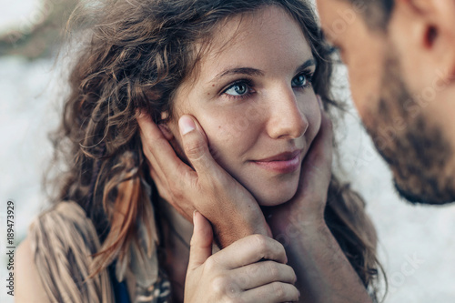 Man holding woman face in his hands before kissing. Love ralationships concept photo