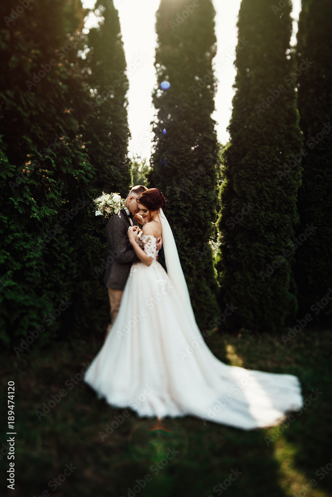 Beautiful young couple walking in the autumn park. The man with tenderness hugs woman Beautiful young couple walking in the autumn park. The man with tenderness hugs woman