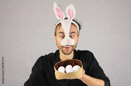 man in the mask Easter rabbit looking at the eggs in hat
