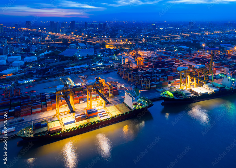 Fototapeta premium Aerial view of Containers yard in port congestion with ship vessels are loading and discharging operations of the transportation in international port.Shot from drone.