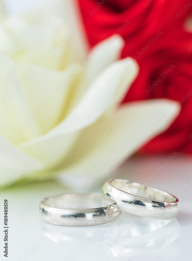 Red rose and wedding ring on white