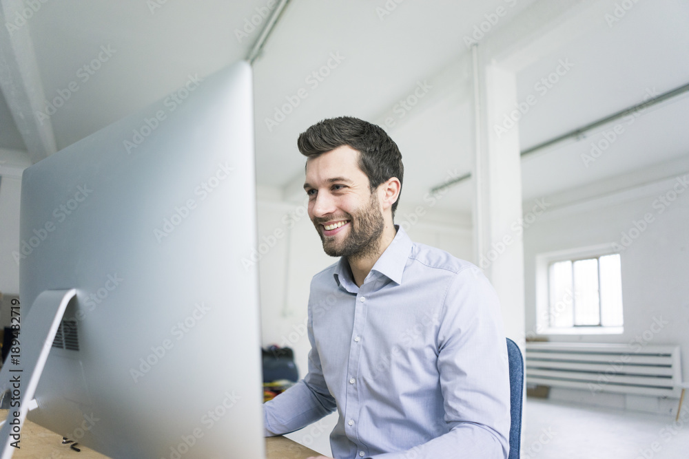 Smiling businessman working at desk in office Smiling businessman working at desk in office