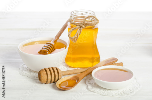 honey in a spoon, a jar and a bowl on wooden table