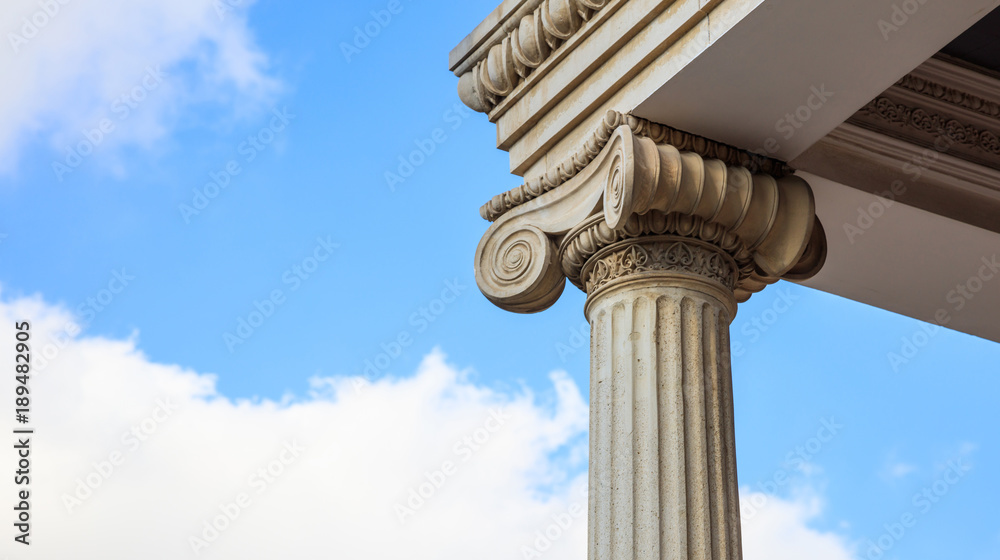 Marble pillar detail. Ancient ionic column of white ornate marble. Blue sky, under, close up view, banner