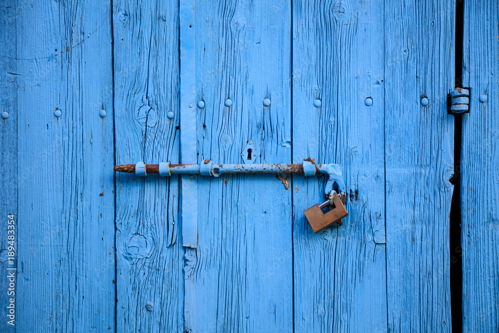 Wooden bright blue, empty, old door for background. Rusty latch, padlock. Close up, banner, details