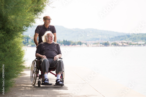 Senior In Wheelchair Spending Time Outdoors With His Nurse