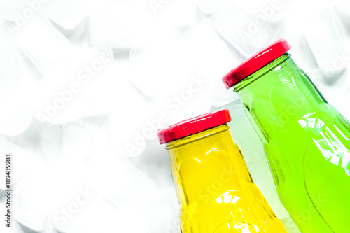 colorful plastic bottles with ice cubes white desk background to