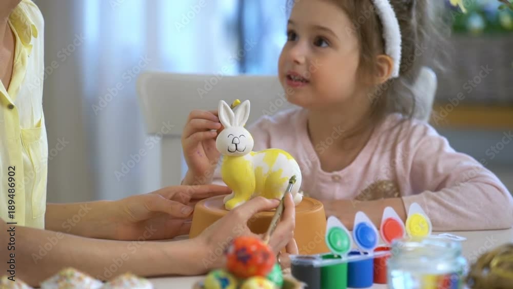 Happy Easter! Mother and her little daughter with bunny ears painting Easter Bunny at the festive table with basket and eggs. Slow Motion Happy Easter! Mother and her little daughter with bunny ears painting Easter Bunny at the festive table with basket and eggs. Slow Motion