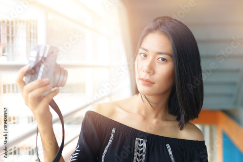 Asian women holding camera Take her picture outdoors.
