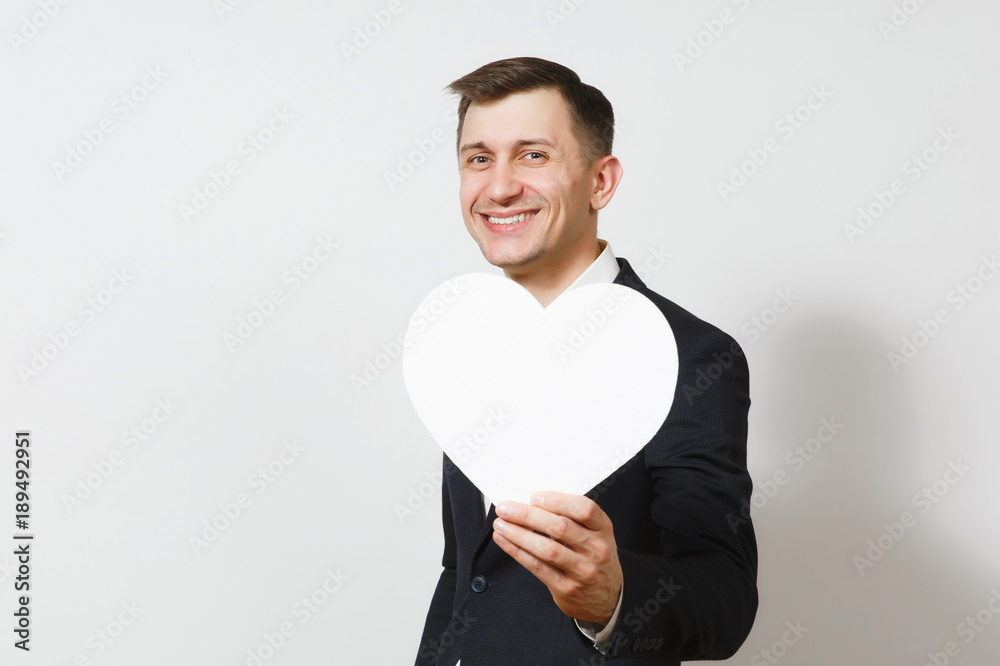 Young handsome man in suit holding big white heart isolated on white background. Copy space, advertisement. Place for text. St. Valentine's Day, International Women's Day, birthday, holiday concept. Young handsome man in suit holding big white heart isolated on white background. Copy space, advertisement. Place for text. St. Valentine's Day, International Women's Day, birthday, holiday concept.