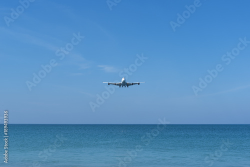 Airplane landing over the blue sea