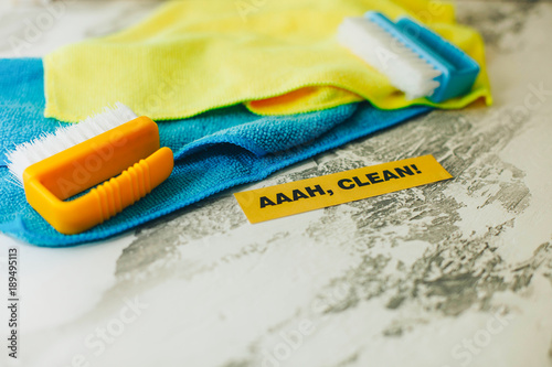 Ready for cleanup. Blue and yellow cleaning tools on a light concrete background. Printed Aaah, Clean inscription, flat lay, top view photo