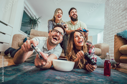 Obraz na płótnie Group of friends play video games together at home, having fun.