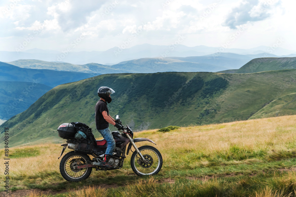 Motorcyclist on a mountainous road, cold overcast weather. Extreme sport, active lifestyle, adventure touring concept. High mountains, dirt roads. enduro off road touring