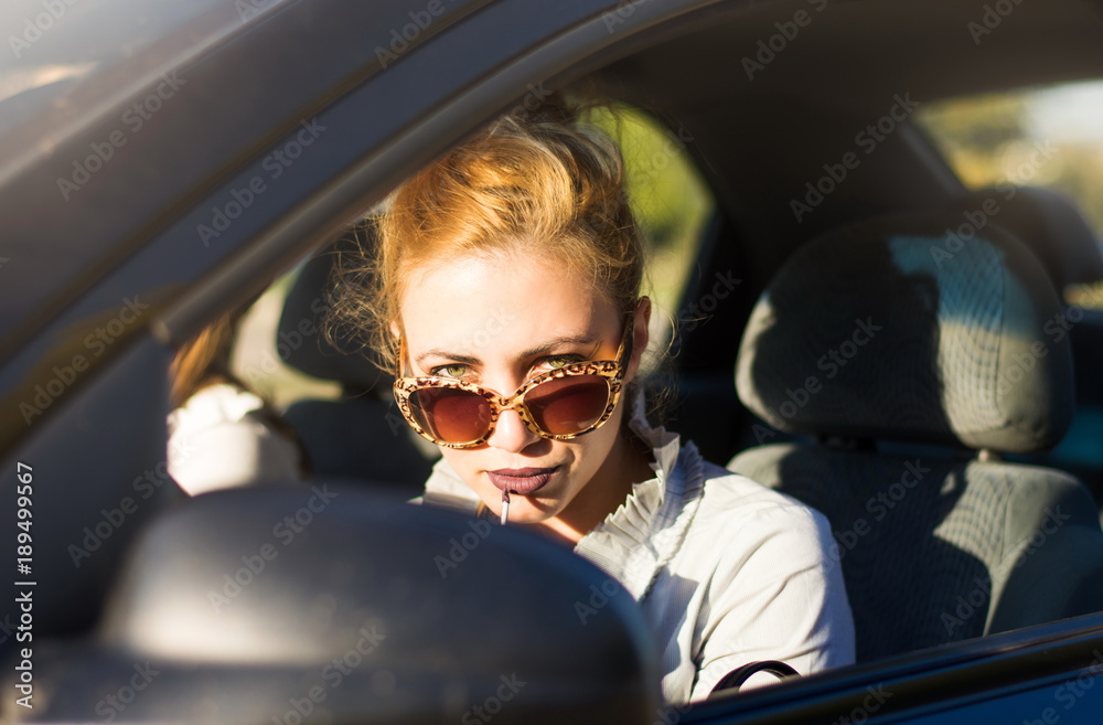 Female driver applying lipstick in a car Female driver applying lipstick in a car