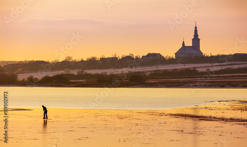 Принти на полотні undefined person skating on the frozen lake in evening