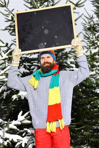 Handsome bearded man, smiling guy in grey sweater holds blackboard