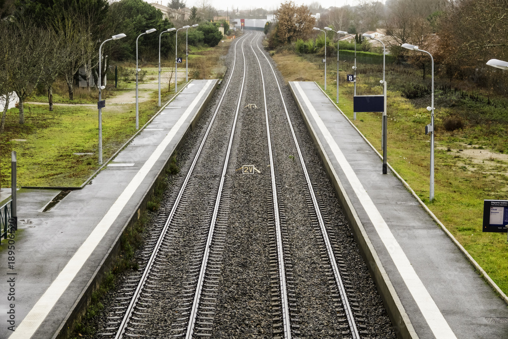 The railroad tracks stretch to the horizon and turn. Two ruts pass between the empty platforms of a small provincial station. The railroad tracks stretch to the horizon and turn. Two ruts pass between the empty platforms of a small provincial station.