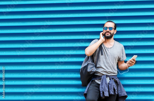 man with earphones and smartphone over wall