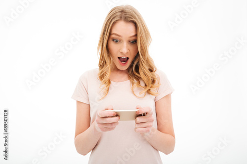 Shocked young woman play games by mobile phone.