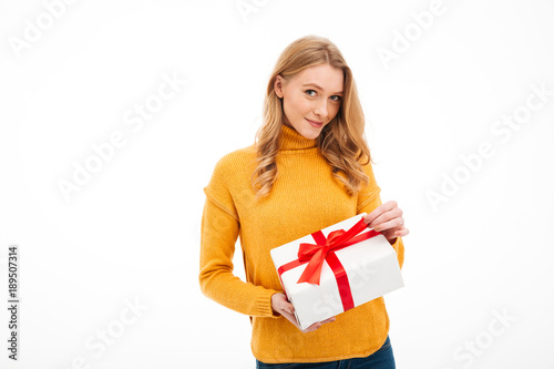 Cute cheerful young woman holding surprise gift box.