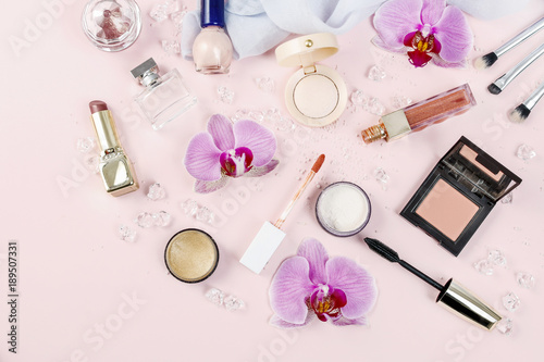 Cosmetics and flowers on pink background.