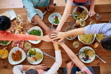 people holding hands together over table with food
