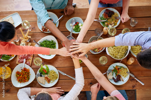 people holding hands together over table with food