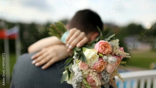 wedding couple hugging, the bride holding a bouquet of flowers in her hand